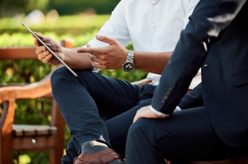 people at a park bench on tablet
